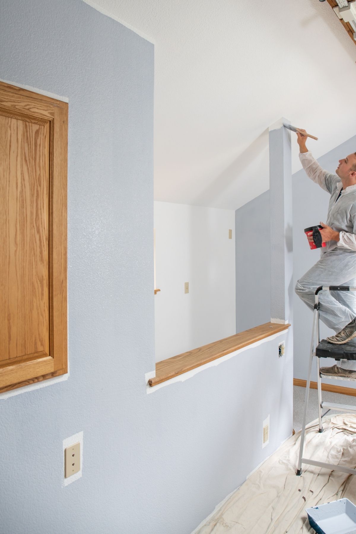 Peintre professionnel utilisant un rouleau pour peindre un mur intérieur à Chambly